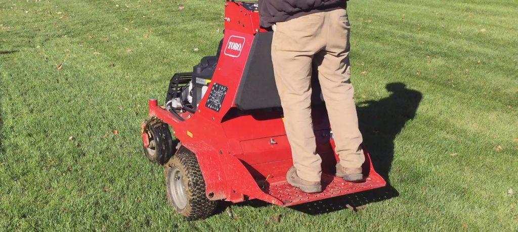 Core Aeration expert using a machine on green lawn in golden light, enriching soil.